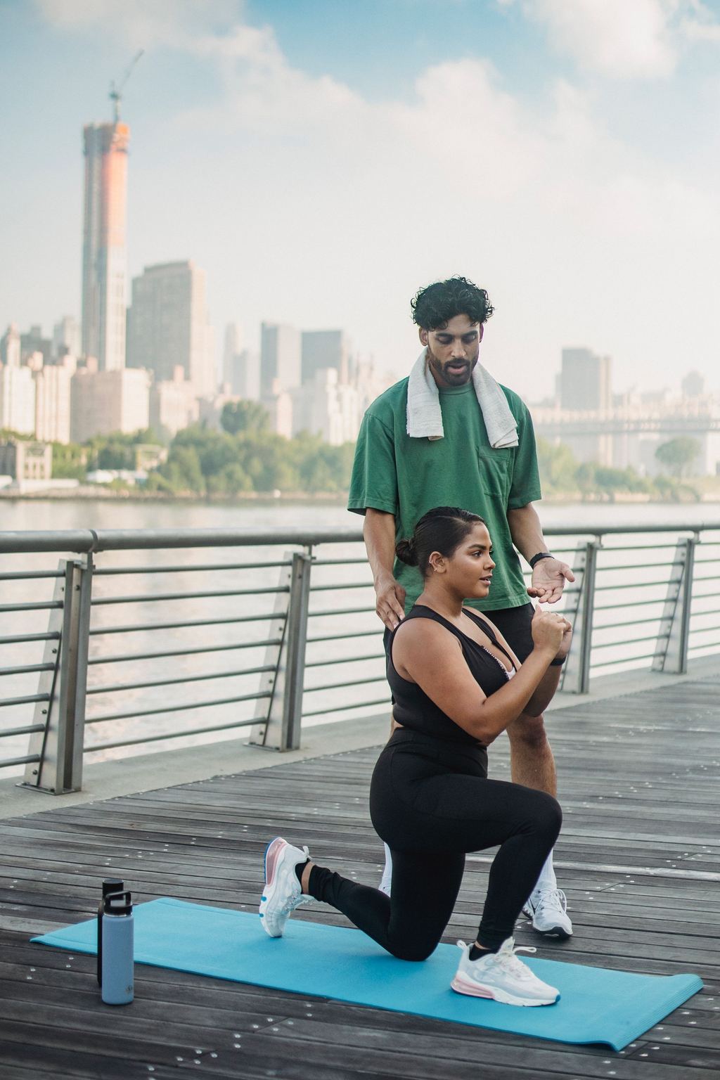 Personal trainer corrigindo o afundo de uma aluna na orla